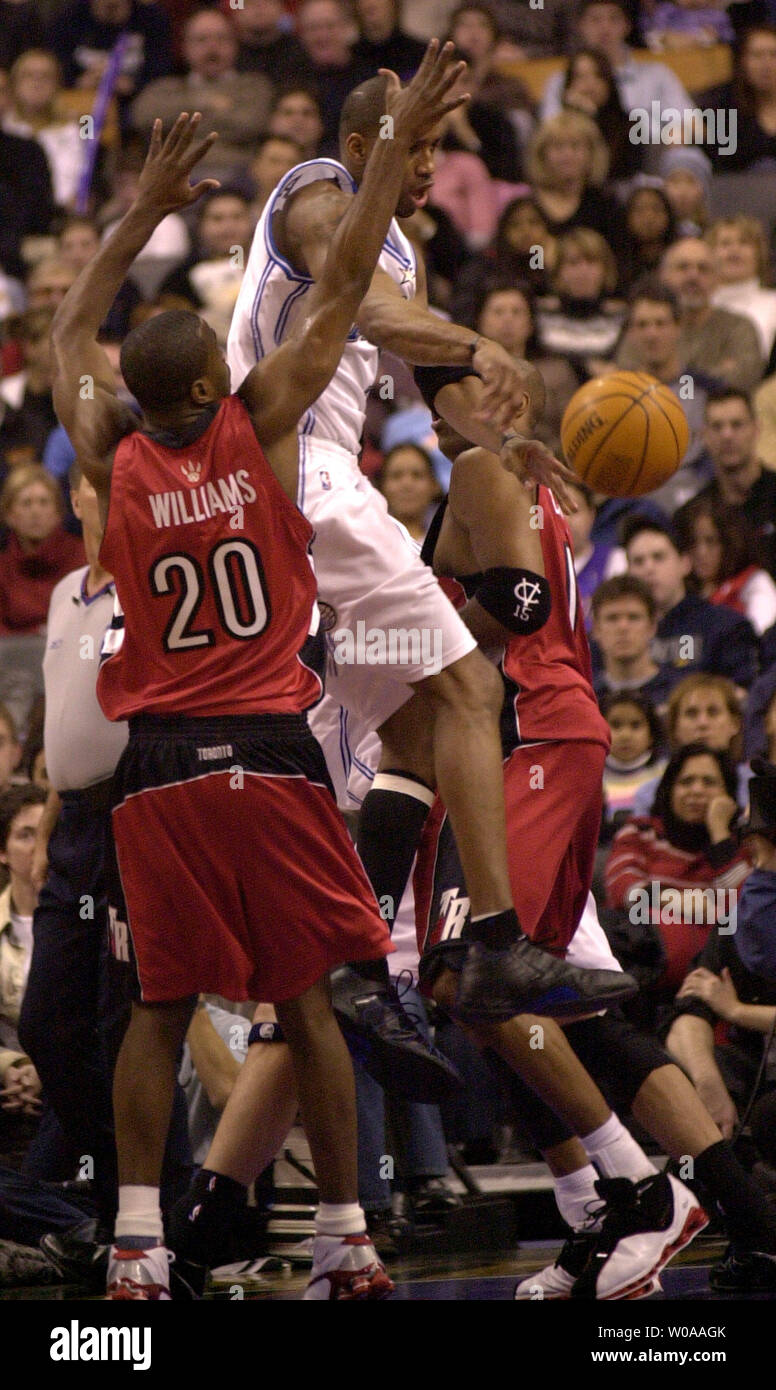 Orlando Magic's Tracy McGrady jumps and passes the ball out of a tight situation as Toronto Raptors' Alvin Williams guards him in first quarter action at the Air Canada Center in Toronto, Canada on Dec. 21, 2003. McGrady scored 29 points to lead the Magic to a 104-91 win over the Raptors. (UPI Photo/Christine Chew) Stock Photo