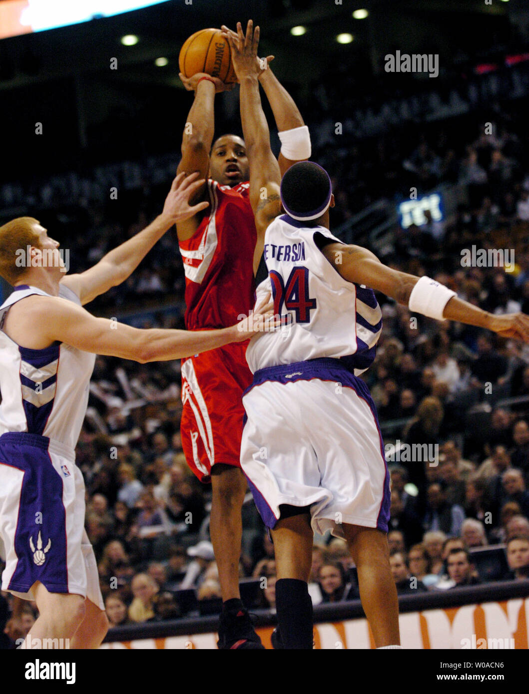 Houston Rockets' Tracy McGrady takes a shot at the basket despite being double-teamed by Toronto Raptors' Morris Peterson and Matt Bonner during first quarter action at the Air Canada Center on January 6, 2006 in Toronto, Canada. McGrady led all scorers with 37 points on the night but the Raptors defeated the Rockets 112-92. (UPI Photo/Christine Chew) Stock Photo