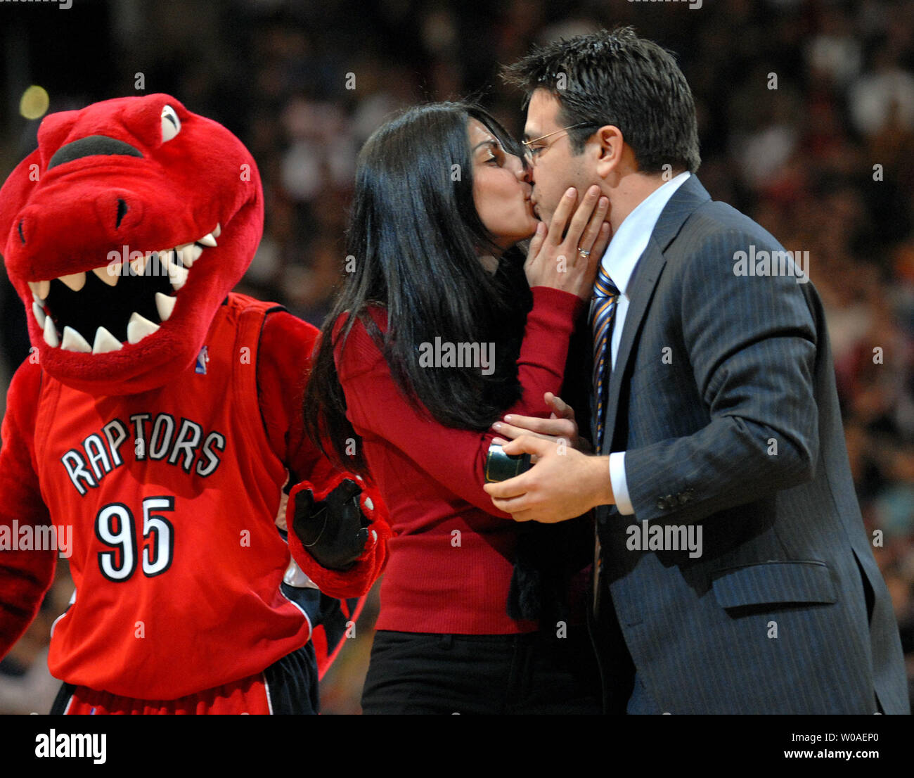 The Raptor mascot walks by to congratulate a couple as they kiss after getting engaged on court during a timeout in the second quarter as the Toronto Raptors host the New Jersey Nets in the Valentine's Day game at the Air Canada Center in Toronto, Canada on February 14, 2007. The Raptors defeated the Nets 120-109. (UPI Photo/Christine Chew) Stock Photo