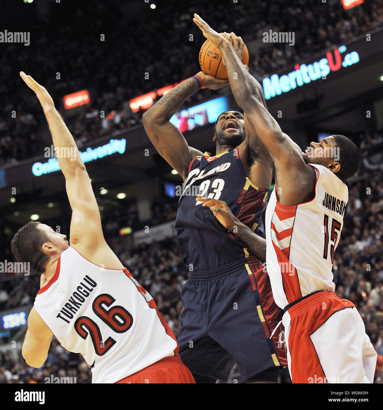 Cleveland Cavaliers' LeBron James (center) takes a shot at the basket as  Toronto Raptors' Hedo Turkoglu (L) and Amir Johnson double-team him in  second quarter action of the Raptors' home opener at