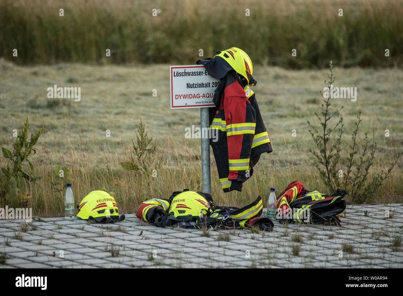 Heinsdorfergrund, Germany. 26th June, 2019. Firefighters have hung their  clothes on a fence after a fire in front of an electroplating company. The  company's production hall in the Unterheinsdorf industrial estate south