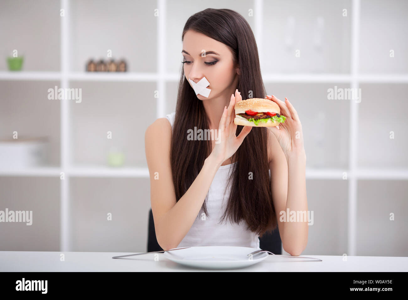 Diet. Close up face of young beautiful sad latin woman with mouth sealed on stick tape Stock Photo