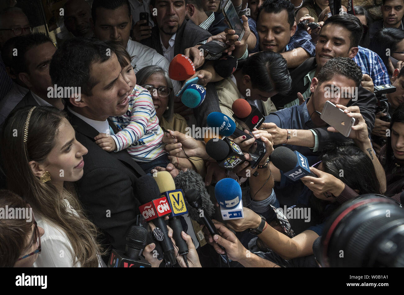 Opposition leader and self-proclaimed 'acting president' Juan Guaido (L) talks to the press as he holds his daughter Miranda, next to his wife Fabiana Rosales , outside his home in Santa Fe, Caracas on January 31, 2019. Venezuela's opposition leader Juan Guaido was to outline his plans to tackle the country's economic crisis Thursday after European lawmakers recognized him as the acting head of state -- another step forward in his bid to force out President Nicolas Maduro. photo by Marcelo Perez/ UPI Stock Photo