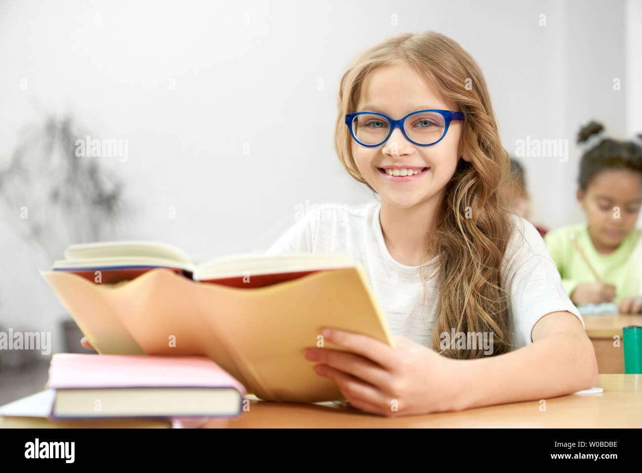 Portrait Of Young Schoolgirl In Blue Glasses With Opened Book In