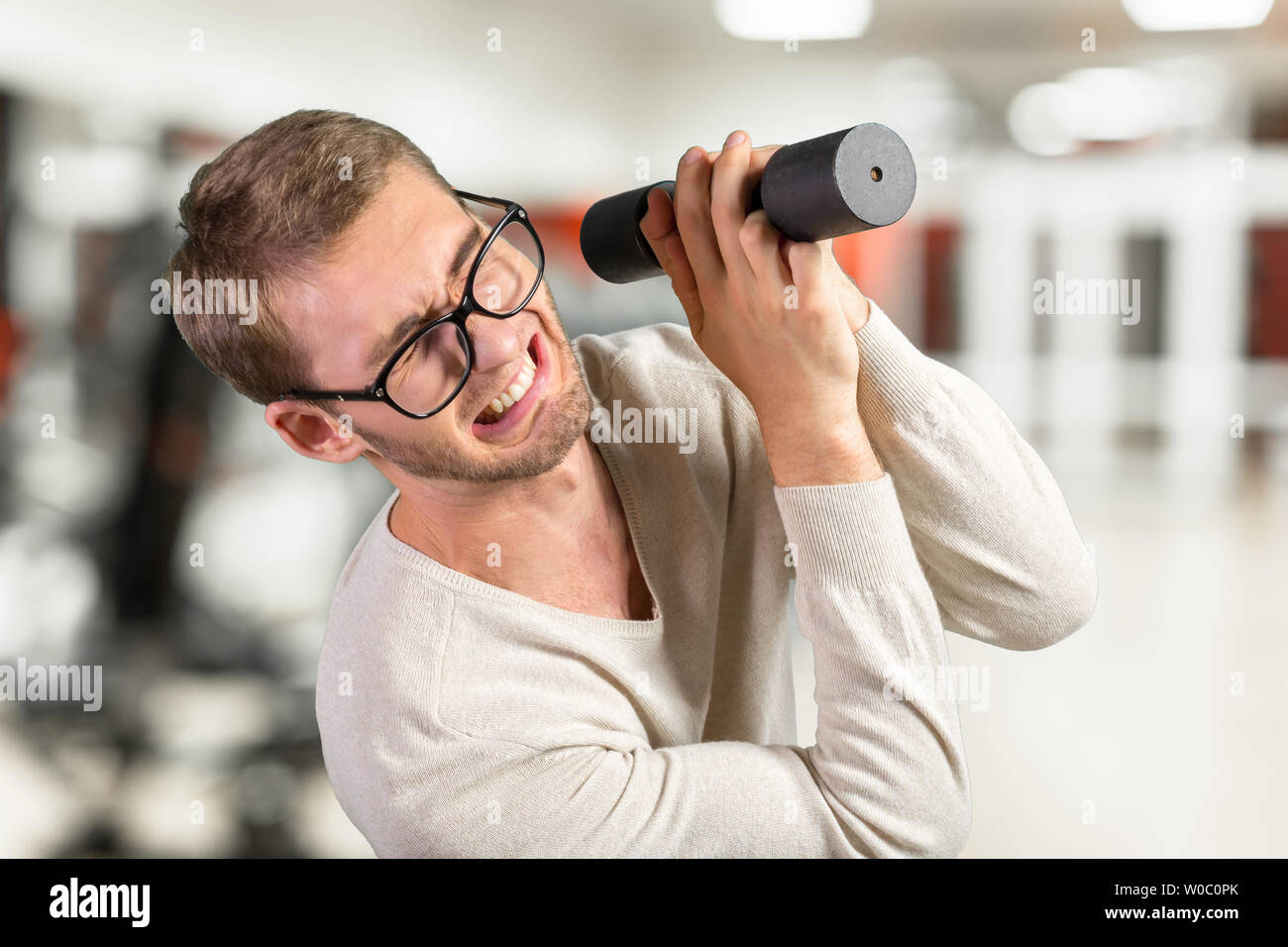 Funny weak man tries to lift a weight Stock Photo Alamy