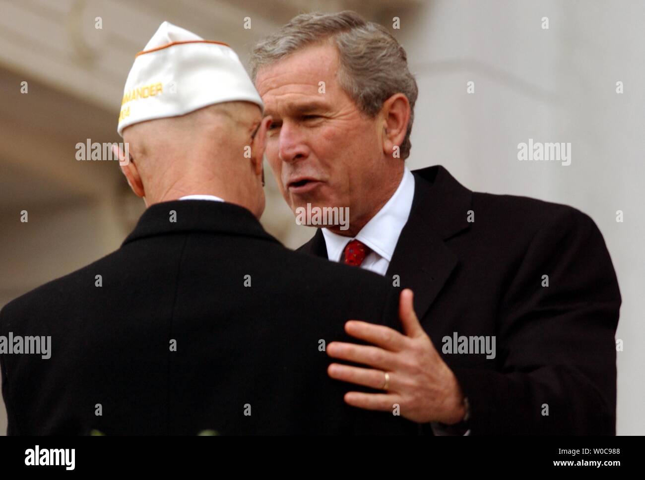 President George W. Bush congradulates David Berger, National Commander of the Army and Navy Union, after his speach during a memorial ceremony near the tomb of the unknown soldier on Veterans Day, November 11, 2003 in Arlington National Cemetery in Arlington, Virgina. (UPI/Michael Kleinfeld) Stock Photo