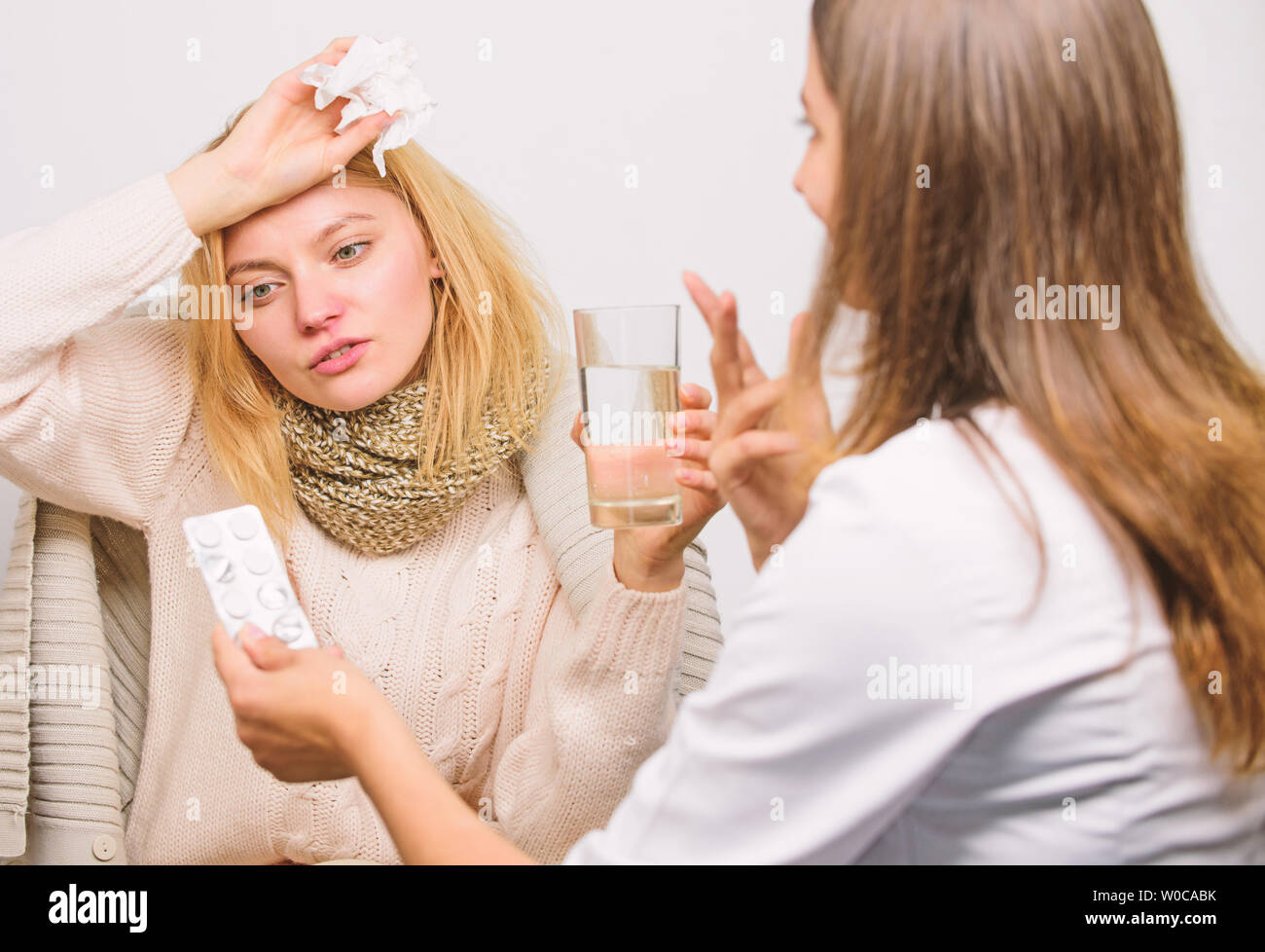 Tips how to get rid of cold. Recognize symptoms of cold. Remedies should help beat cold fast. Woman consult with doctor. Girl in scarf hold tissue while doctor offer treatment. Cold and flu remedies. Stock Photo