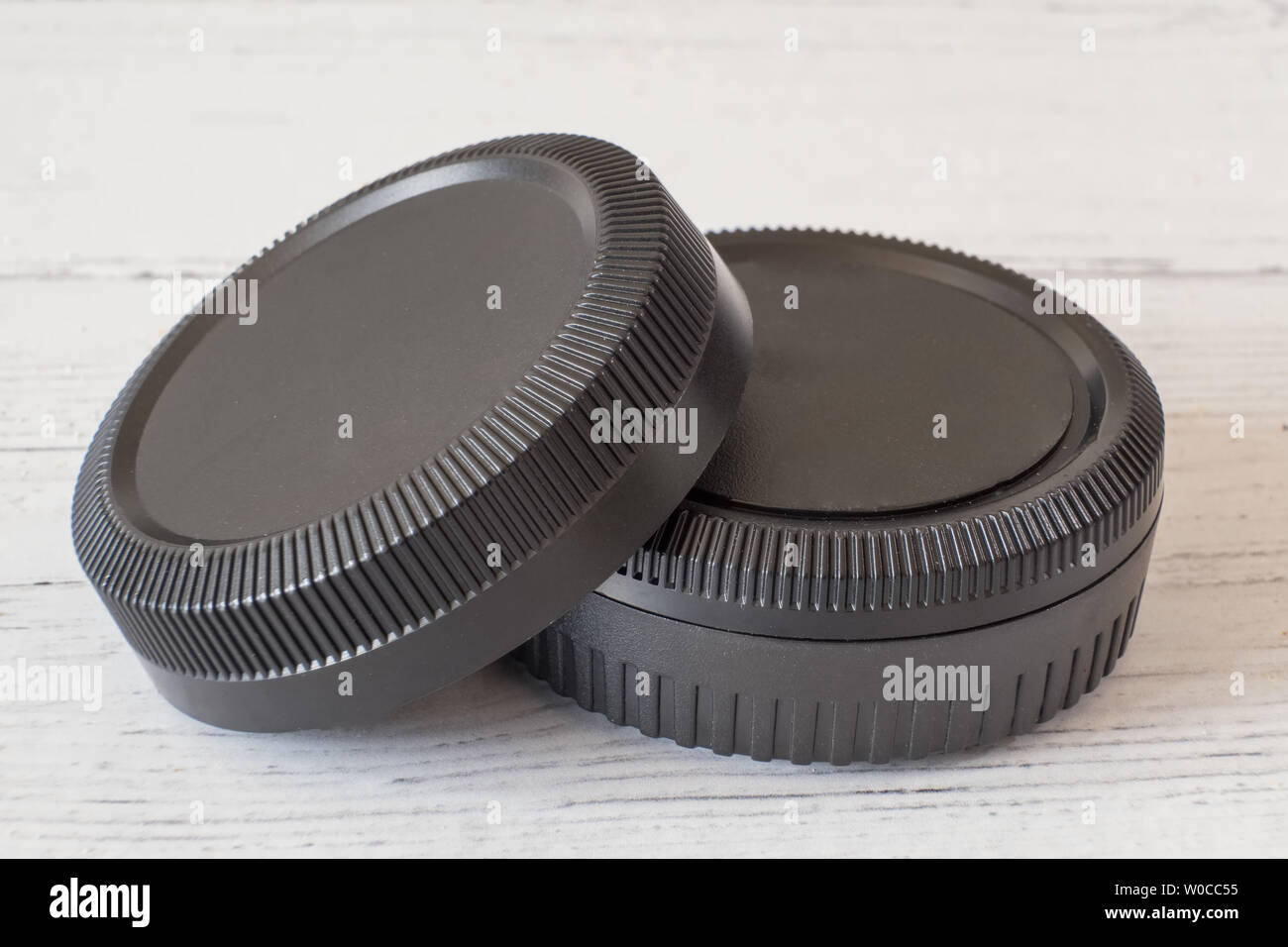 Camera lens caps and body covers on white painted wooden surface Stock