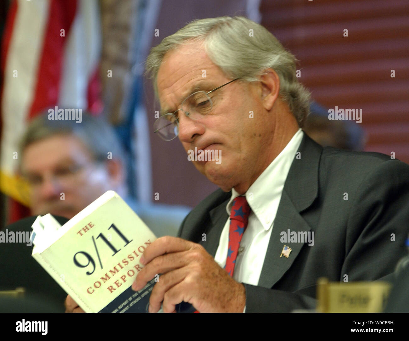 Newly nominated Director of the CIA Rep. Porter Goss, R-FL, reads a copy of the 9/11 Commission's report while Thomas Kean, not shown, testifies before the Full House Intelligence Committee on August 11, 2004 in Washington.  The committee is examining the 9/11 Committee's recommendation to create an intelligence chief to over see all of America's intelligence services.   (UPI Photo/Michael Kleinfeld) Stock Photo