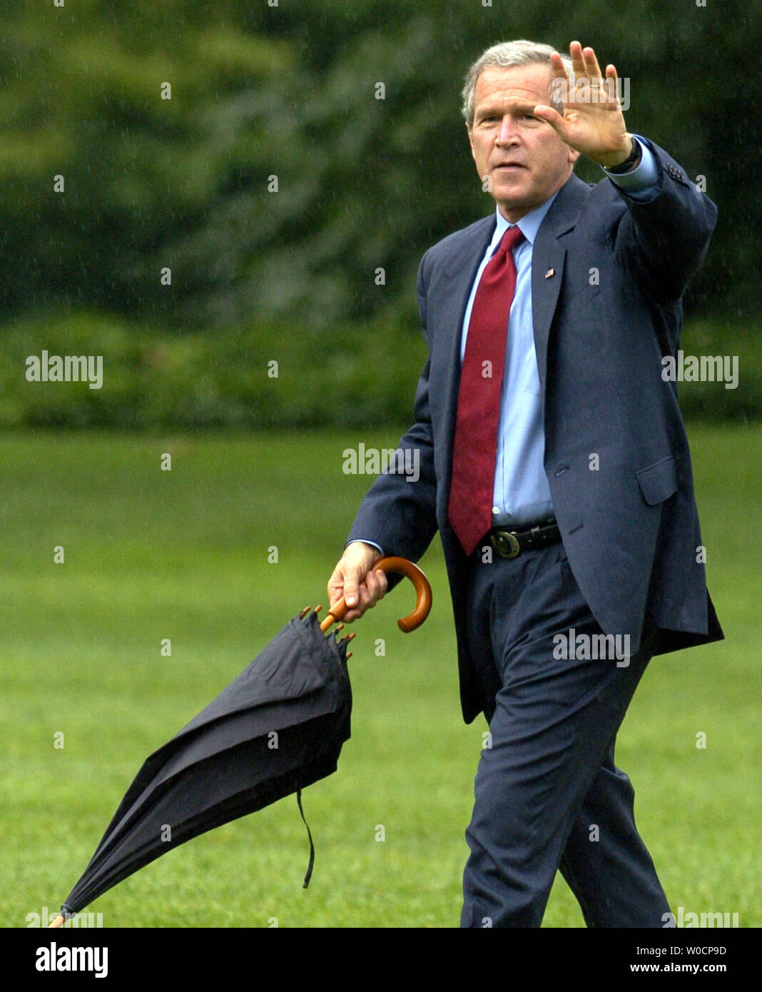 US President George W. Bush carries an umbrella in a light drizzle as he arrrives at the White House after a day trip to North Carolina, July 15, 2005.  Bush visited a factory and make remarks on the CAFTA treaty.       (UPI photo/Mike Theiler) Stock Photo