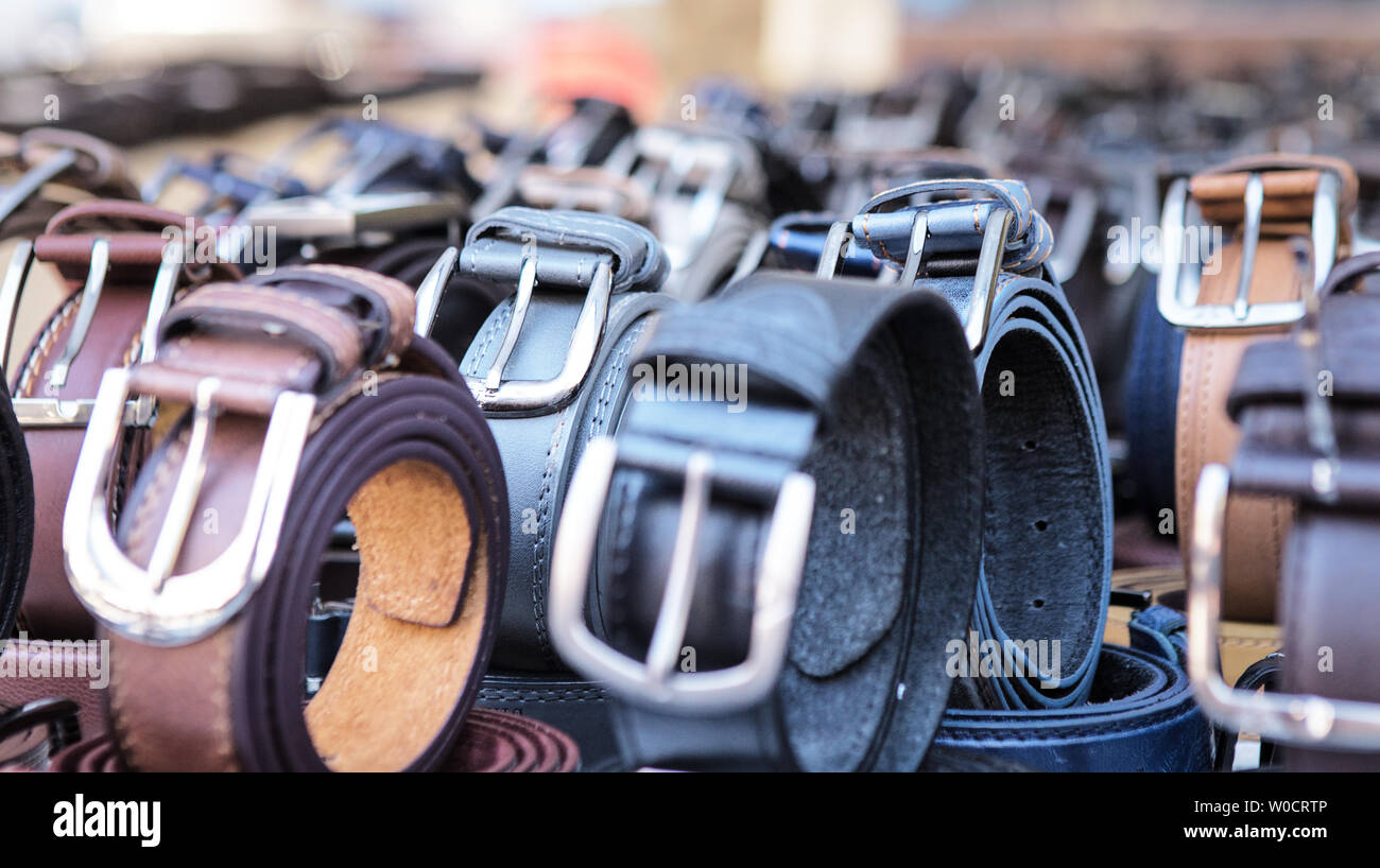 lots of rolled up leather belts for sale on a market stand Stock Photo