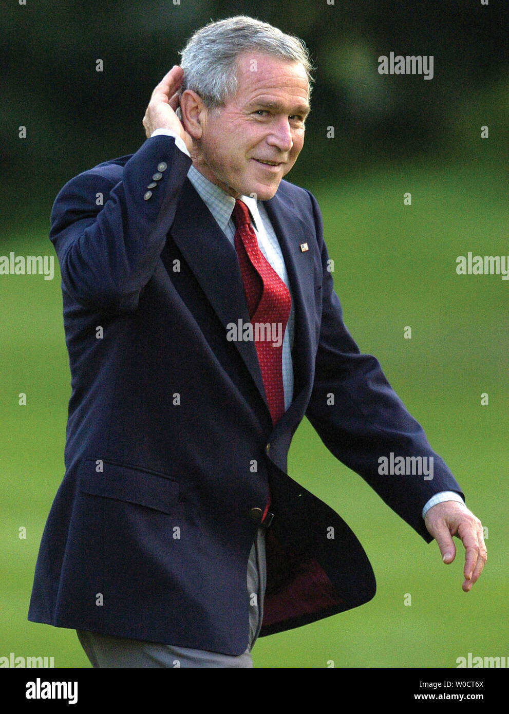 US President George W. Bush cups his ear to hear reporter's questions as he returns to the White House from a day trip to Florida to be briefed on relief efforts after Hurricane Wilma, October 27, 2005. Bush did not answer questions about Harriet Miers' decision to withdraw her Supreme Court nomination earlier in the day.    (UPI Photo/Mike Theiler) Stock Photo