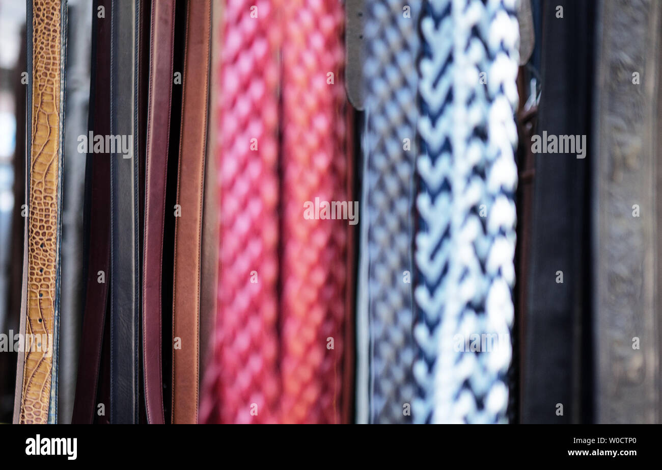 many belts hanging up on a stand out of focus abstract Stock Photo