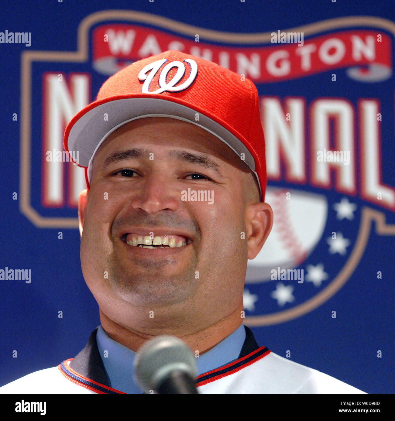 Manny Acta dons his jersey and hat after he was announced as the