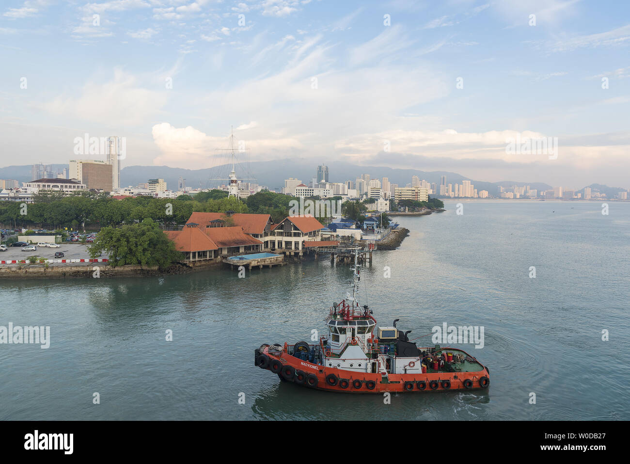 PENANG, MALAYSIA,   Port of Penang, Asia,  Pulau Pinang, George Town, City skyline with harbour tug boat approaching dock. Stock Photo
