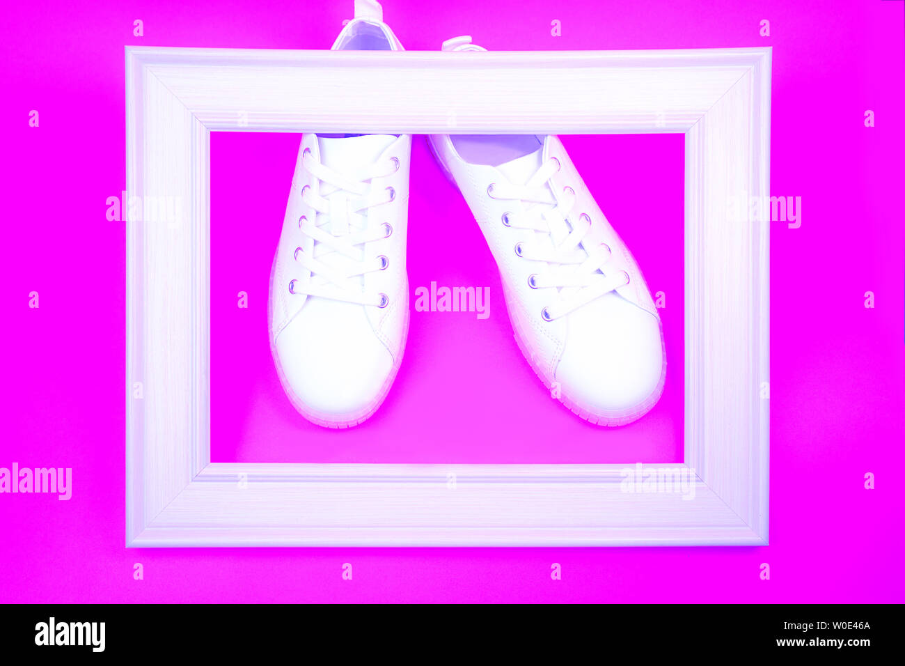 White sneakers and wooden frame on neon pink background Stock Photo - Alamy