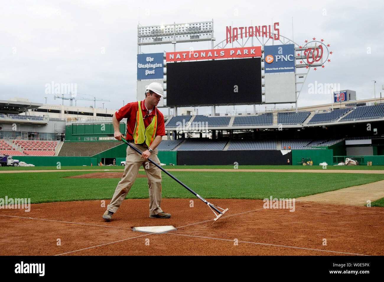 Washington Nationals assistant head groundskeeper John Royse rakes the