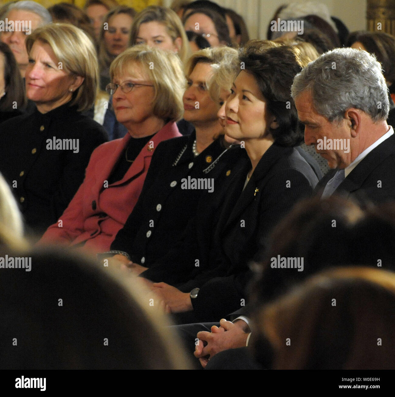 U.S. President George W. Bush listens as First Lady Laura Bush makes Remarks in Honor of Women's History Month and International Women's Day in the East Room of the White House in Washington on March 10, 2008. From left are Rep. Shelley Moore Capito, R-WV, Rep. Judy Bigger, R-IL, Rep. Carolyn Maloney, D-NY, Transportation Secretary Mary E. Peters, Labor Secretary Elaine Chao and Bush.  (UPI Photo/Roger L. Wollenberg) Stock Photo