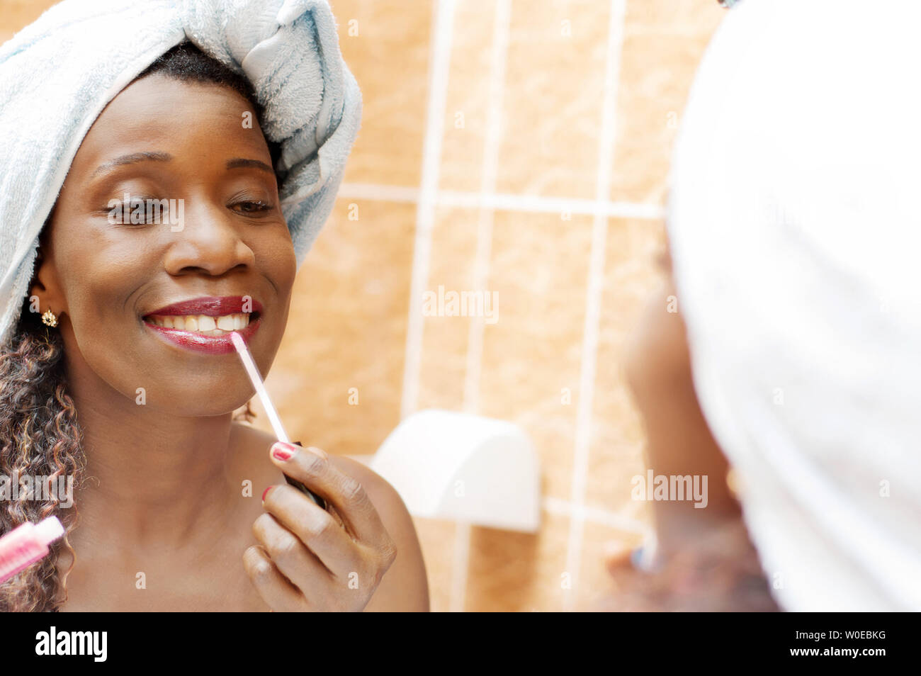 beautiful woman applying makeup in the mirror in the bathroom. Stock Photo