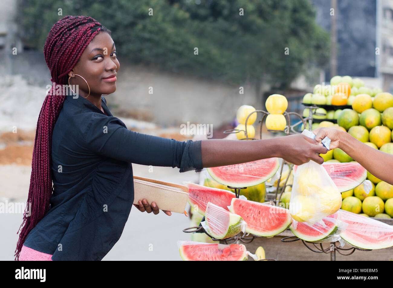 pretty young woman buys food fruits at street market. Stock Photo