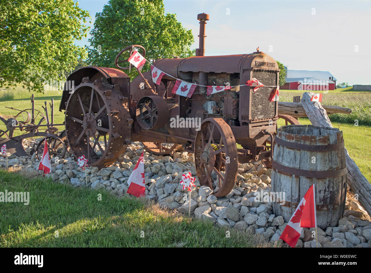 In the countryside, a antique Mc Cormick-Deering tractor bordered with the Canadian flags. The Canada Day. Stock Photo
