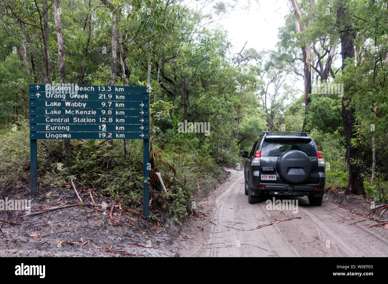 A privately owed  4x4 vehicle passes a road sign deep in the rain forest along a sandy track on Fraser Island off the coast of Queensland in Australia Stock Photo