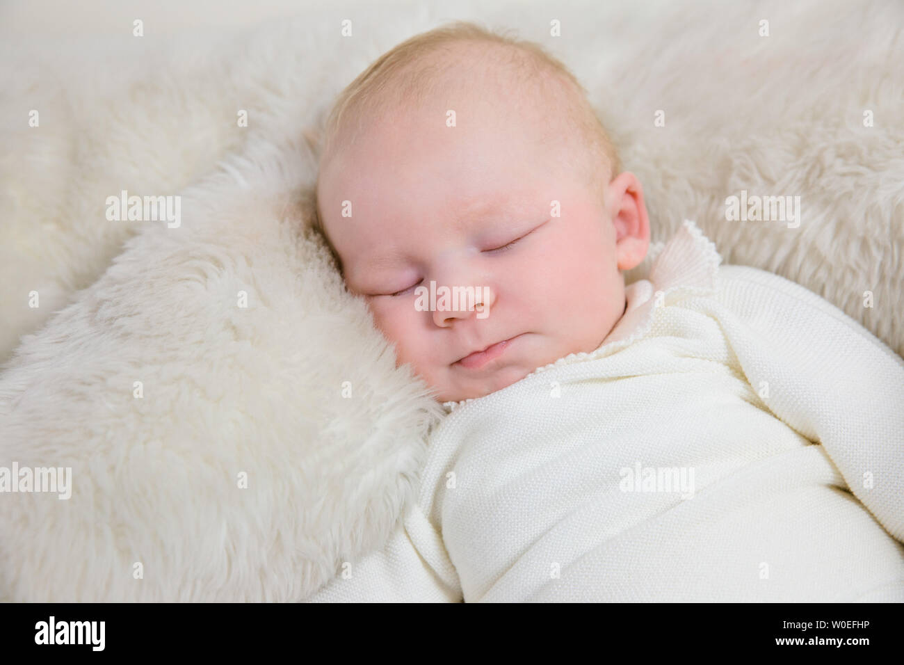 Young infant in white layette of 2 months sleeping  with his big teddy bear. Stock Photo