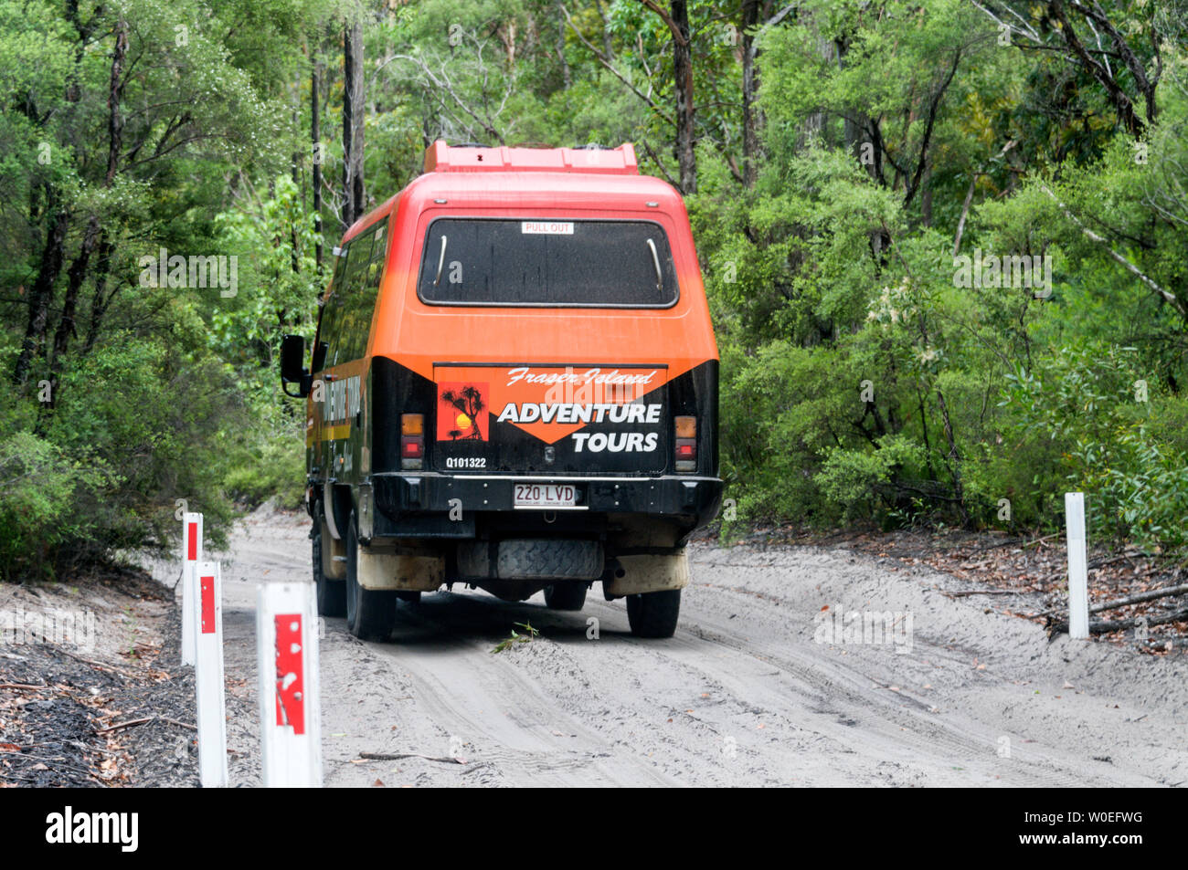 A large tourist carrying vehicle along a sandy track with road markings in the rain forest on Fraser Island off the coast of Queensland in Australia. Stock Photo