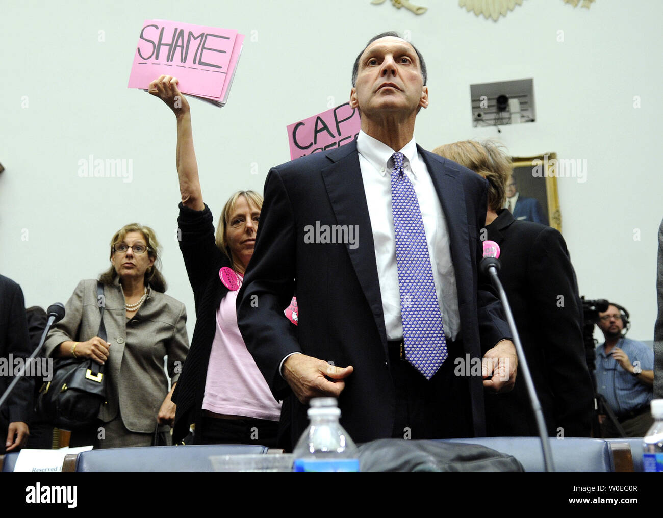 Richard Fuld Jr., Chairman and CEO of Lehman Brothers Holdings, takes his seat as protestors demonstrate behind him, prior to testifying before a House Oversight and Governmental Reform Committee hearing on pic