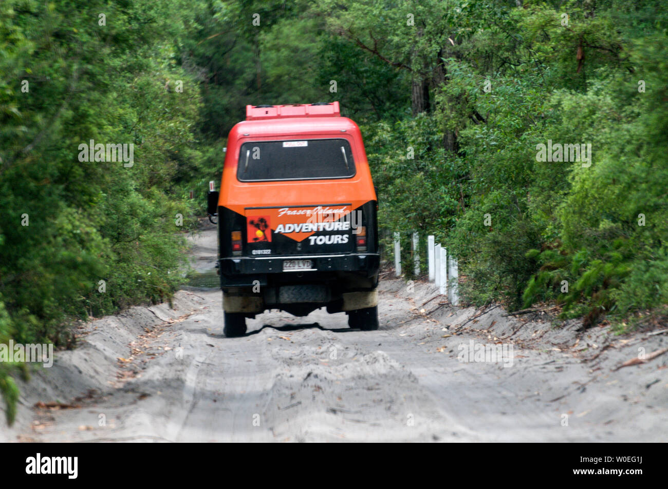 A large tourist carrying vehicle along a sandy track with road markings in the rain forest on Fraser Island off the coast of Queensland in Australia. Stock Photo