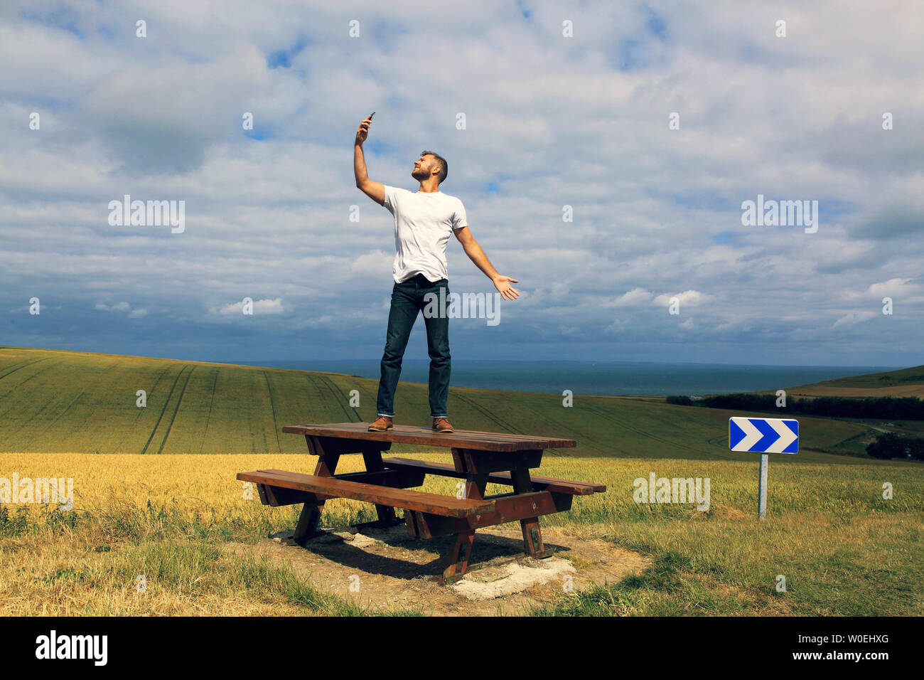 Man with phone standing on picnic table Stock Photo