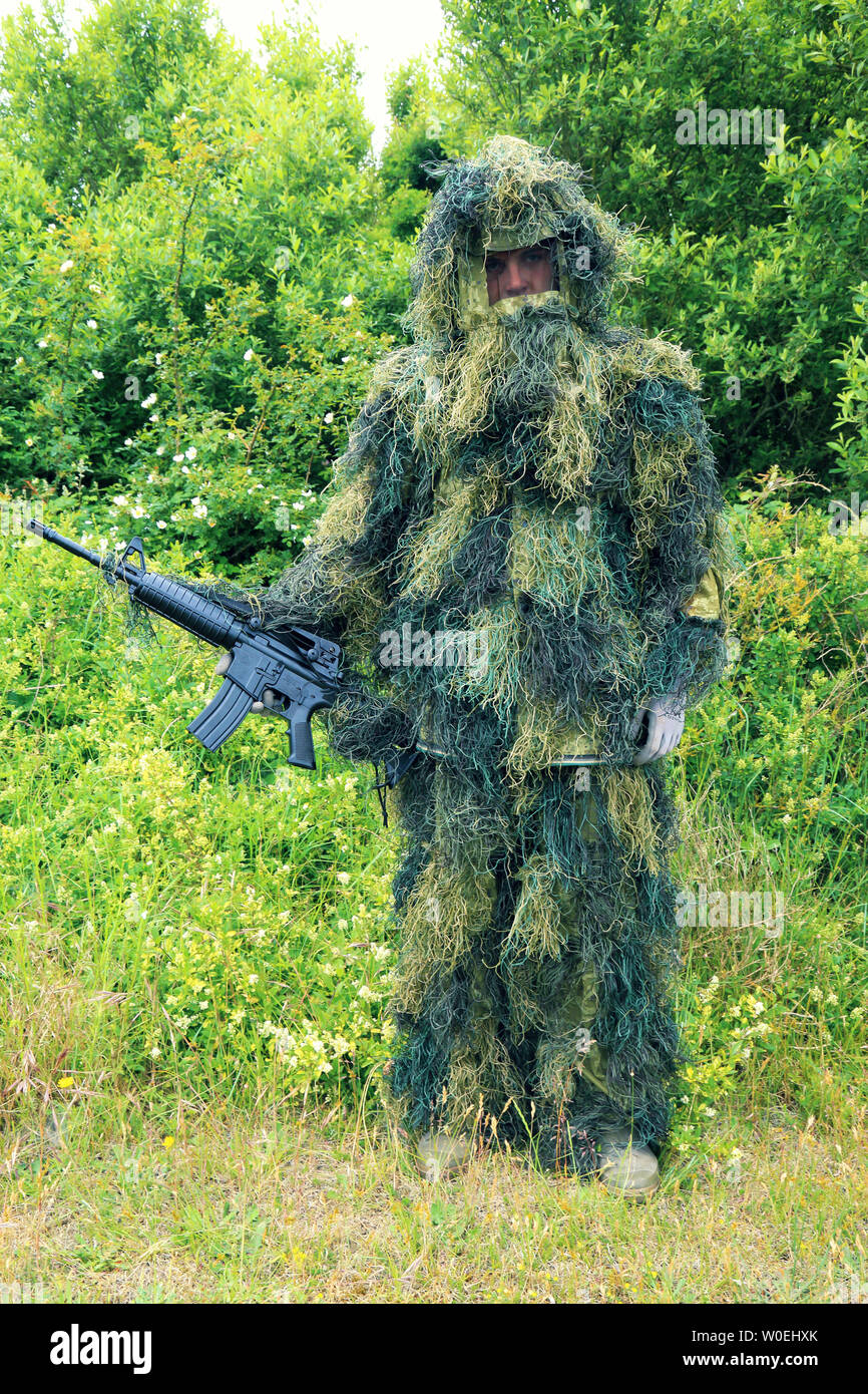 Teenager in ghillie suit with a machine gun Stock Photo