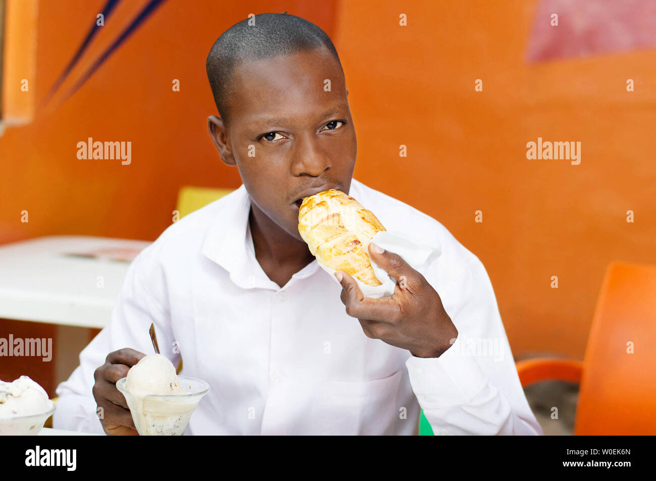 young man sitting  in a restaurant eating his bread accompanied by ice. Stock Photo