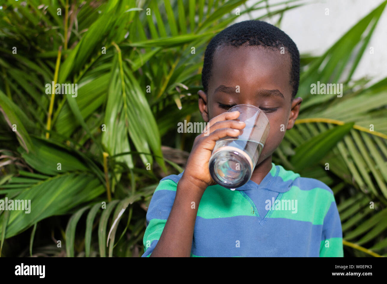 Boy drinking mineral water in a glass. Stock Photo