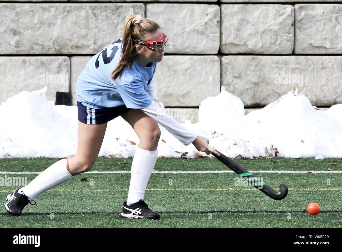 The field hockey player is lining up the ball for a shot. Stock Photo