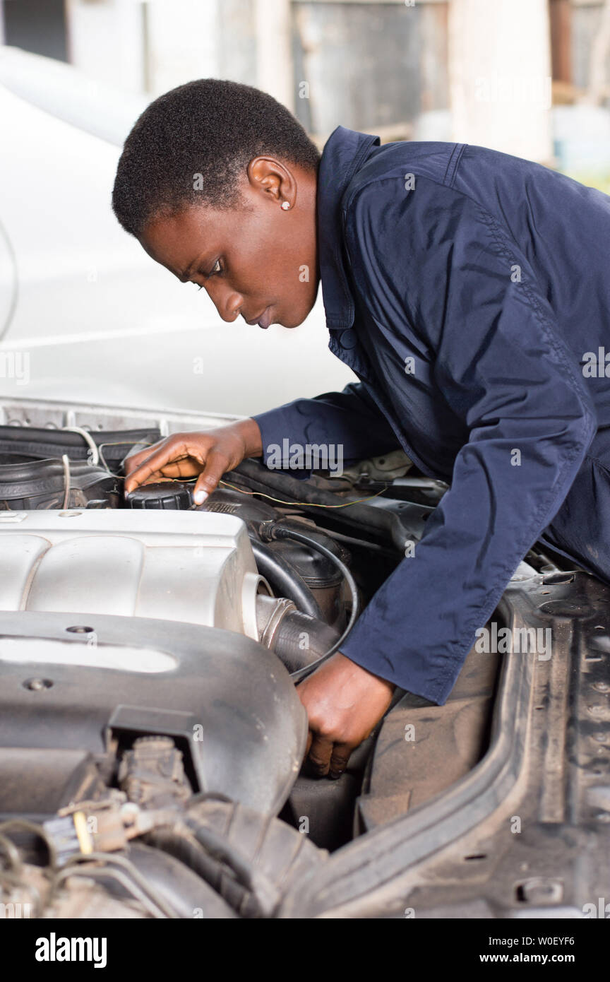 Young female mechanic repairs a car by putting the engine in good condition. Stock Photo
