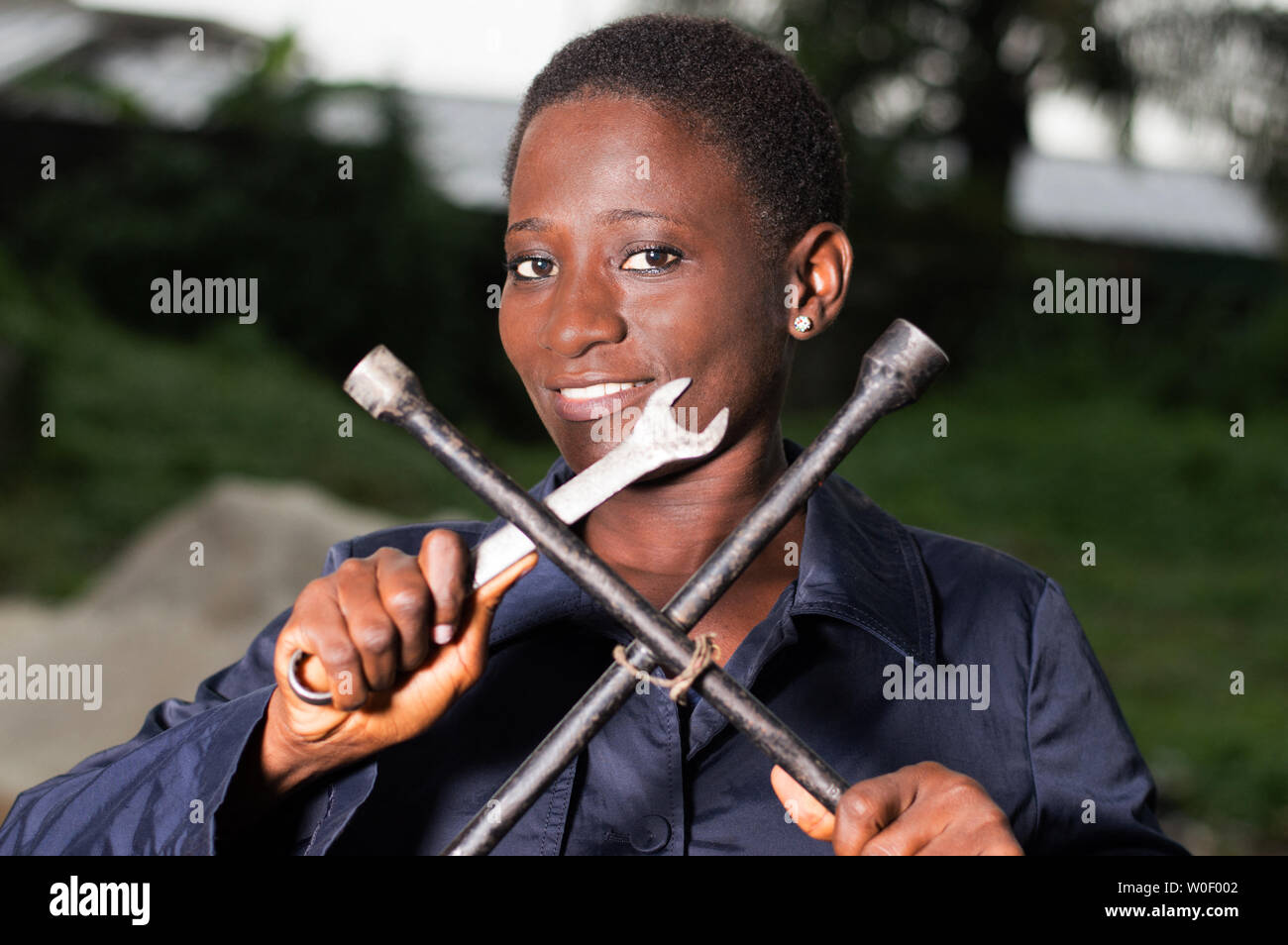 Young smiling mechanic showing her tools in her outdoor studio. Stock Photo