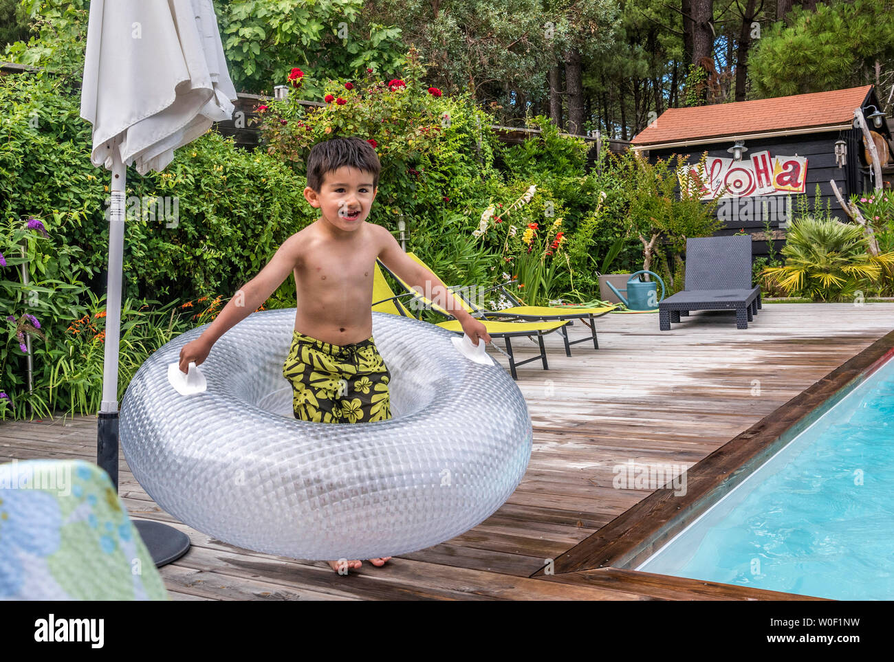 6 year old boy playing with ann inflatable float on the pool deck Stock Photo
