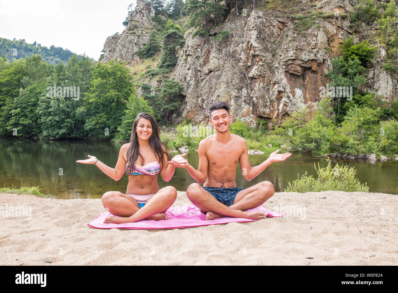 Auvergne - Rhone-Alpes - Haute-Loire - Young couple posing on their beach towel onn the bank of the Loire at Arlemdes under the basalt cliffs. Stock Photo
