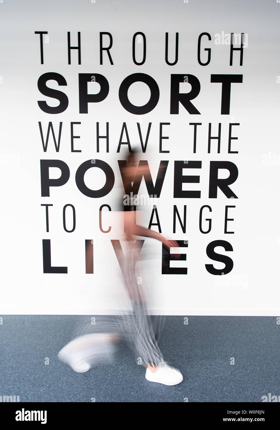 Herzogenaurach, Germany. 26th June, 2019. An employee of "adidas" passes  the key message "Through sport we have the power to change lives" of the  company in the new office building "Arena". In