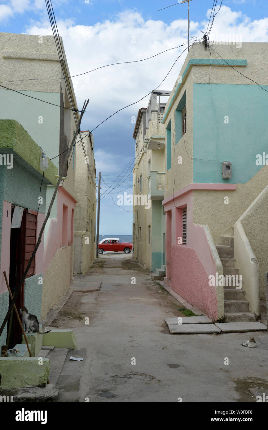 Cuba, Gibara, an old red 50s American car passes at the end of a colorful houses Stock Photo