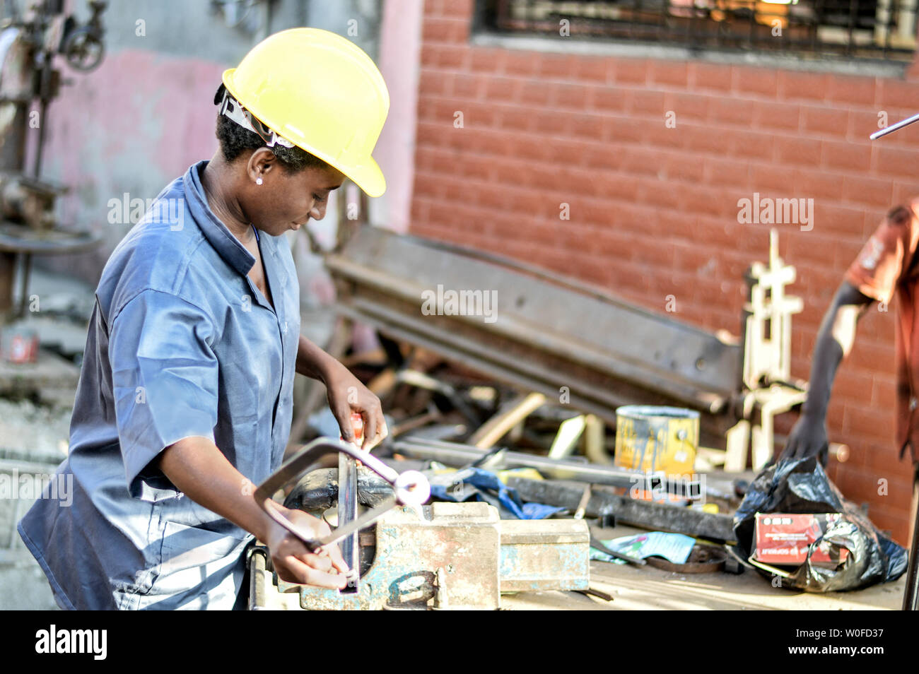 Young woman places an iron bar to cut with a saw. Stock Photo