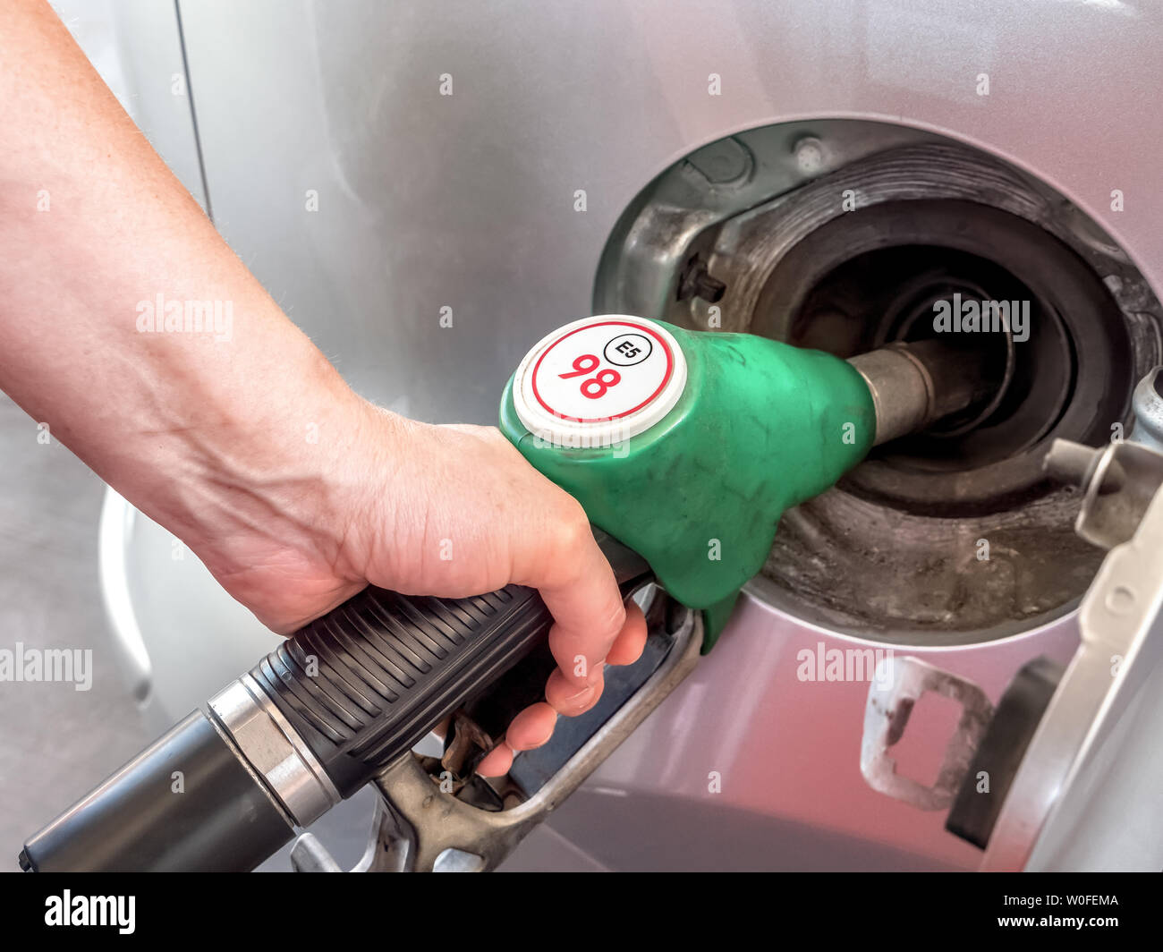 Closeup of female hand topping up car tank with unleaded 98 gasoline Stock Photo