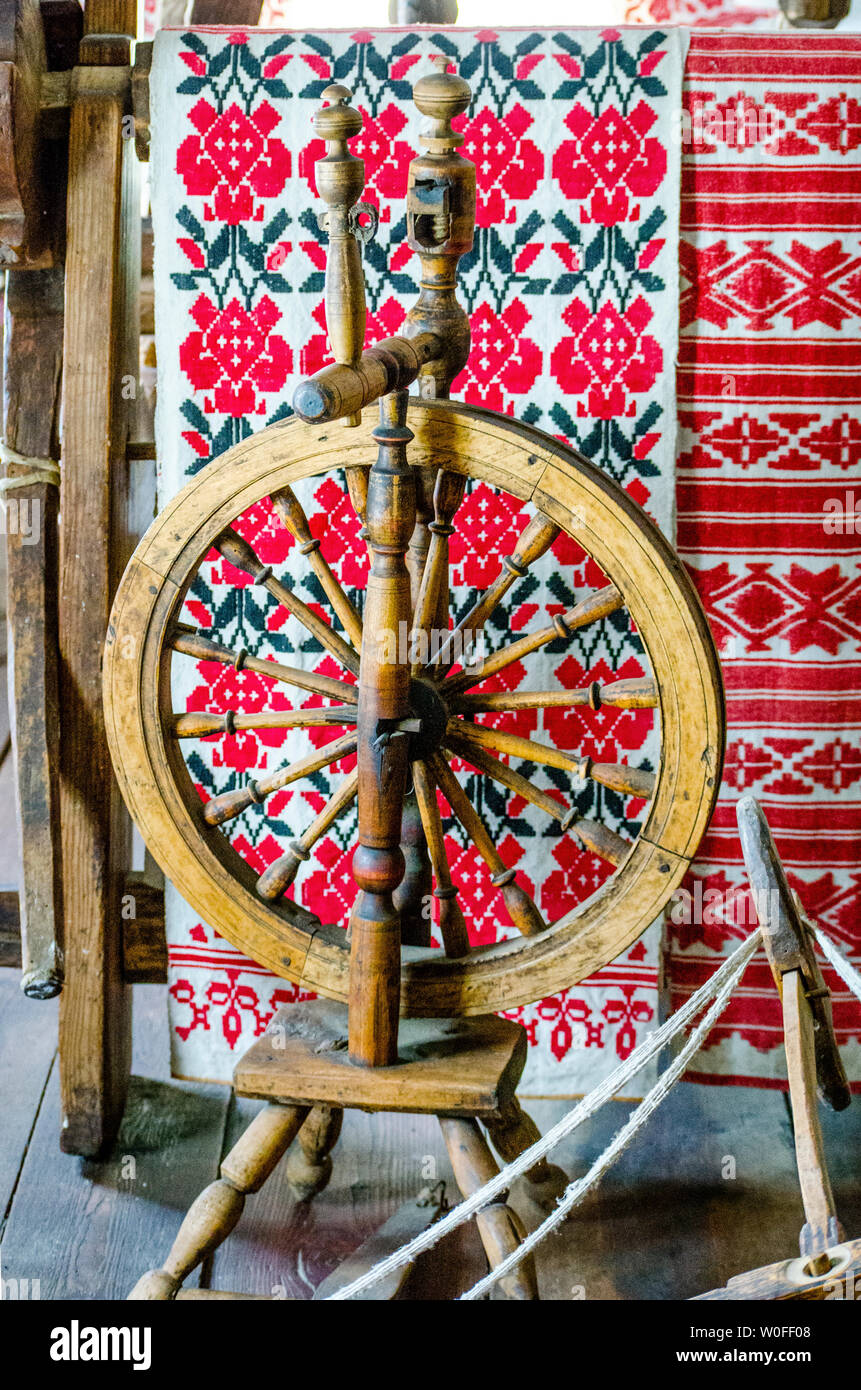 Ancient wooden spinning wheel on the background of a ethnic patterns for embroidery stitch in red and black. Stock Photo