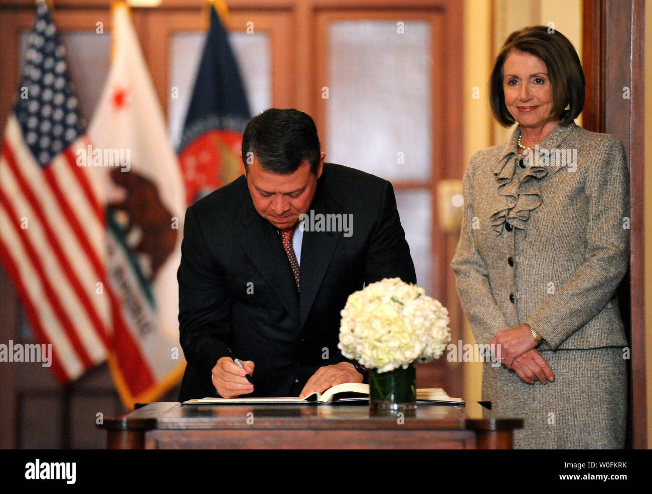 King Abdullah II of Jordan signs a guest book as Speaker of the House Nancy Pelosi watches, prior to their meeting on Capitol Hill in Washington on April 14, 2010.  UPI/Kevin Dietsch Stock Photo
