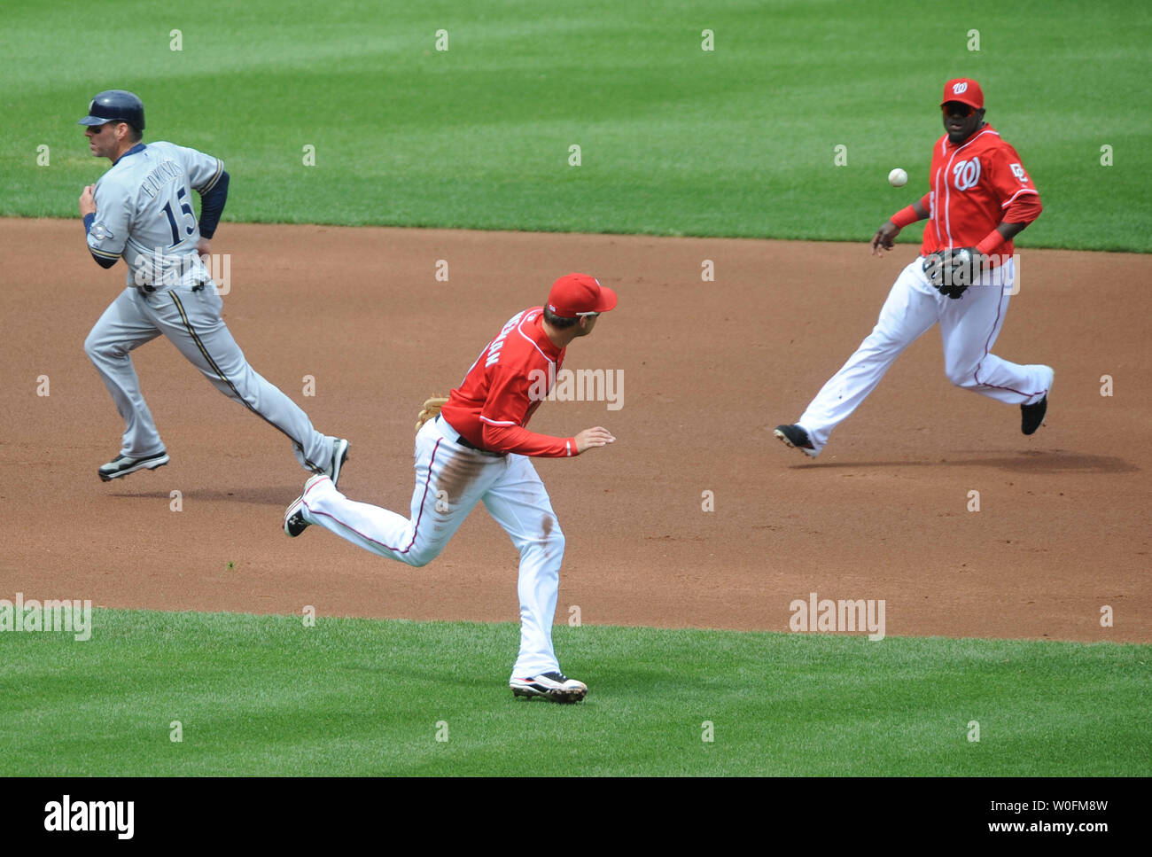 Washington Nationals third baseman Ryan Zimmerman (C) and shortstop Cristian Guzman (R) miss a ground ball as Milwaukee Brewers Jim Edmonds runs to third, during the first inning at Nationals Park in Washington on April 18, 2010.  UPI/Kevin Dietsch Stock Photo