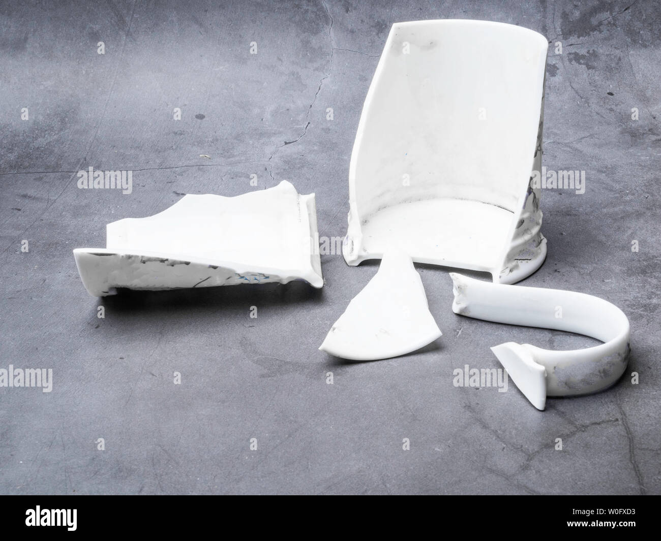 Broken white cup pieces on c0ncrete background Stock Photo - Alamy