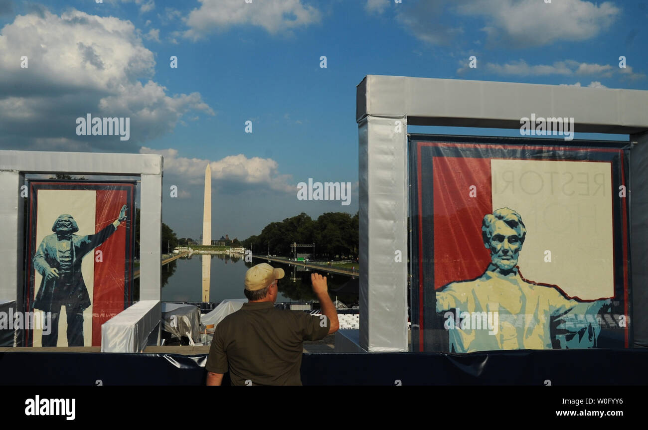 A man takes photos between posters of Frederick Douglass (L) and President Abraham Lincoln, near the Lincoln Memorial and the Washington Monument in Washington on August 27, 2010. Many conservatives have staked out positions near the Memorial for tomorrow's 'Restoring Honor' conservative political rally, organized by Fox News TV host Glenn Beck. Many of America's top conservatives will speak at the rally including former Republican Vice Presidential Candidate Sarah Palin. UPI/Alexis C. Glenn Stock Photo