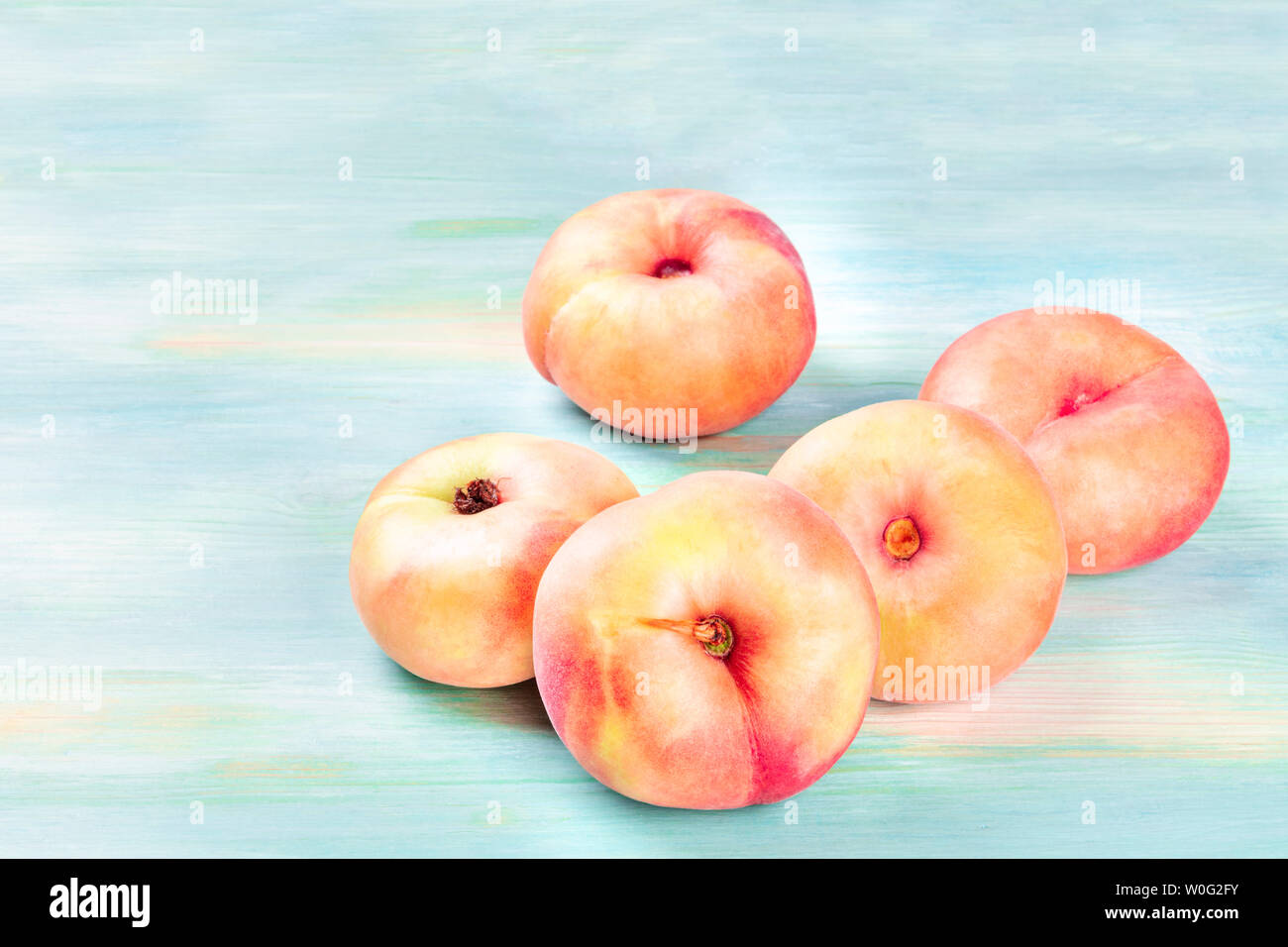 Vibrant organic saturn peaches on a teal background with a place for text Stock Photo