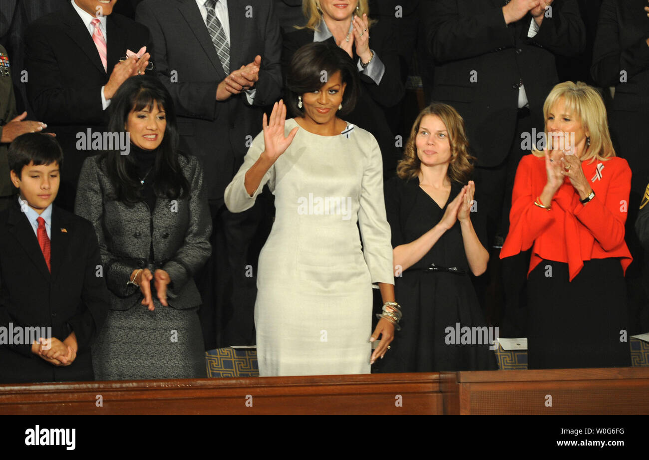 First Lady Michelle Obama waves from her seat in the House Chamber as she arrives to listen to U.S. President Barack Obama deliver his State of the Union address to a Joint Session of Congress in the House Chamber at the U.S. Capitol in Washington on January 25, 2011.  To her right is Roxanna Green, the mother of Christina Taylor Green, 9, who was killed in the January 8th killings in Tucson Arizona, and her son Dallas,11. At right is Dr. Jill Biden.   UPI/Pat Benic Stock Photo